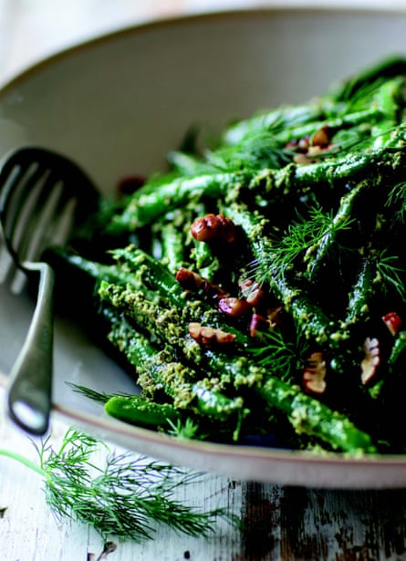 Close-up of a dish of green beans with a dill and pecan dressing.