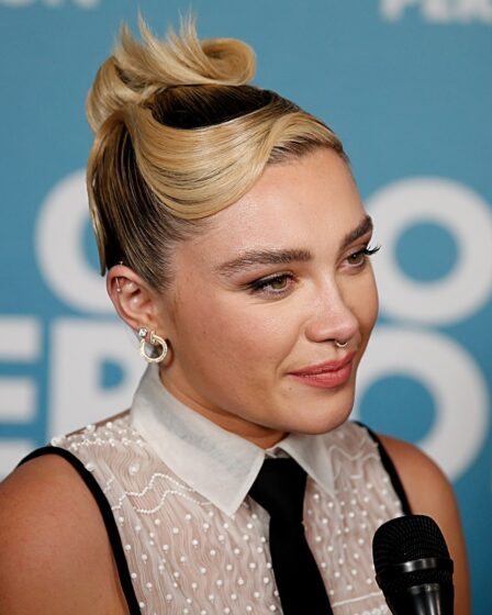 headshot of florence pugh with hair slicked into a topknot with faux side bang