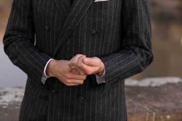 detail of a double-breasted gray chalkstripe flannel suit styled with a white shirt and black tie