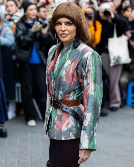 Lisa Rinna poses outside of Vivienne Westwood in Paris wearing a patterned jacket. Her hair is cut in a curledunder bowl...