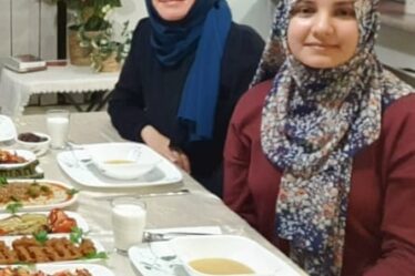Two Muslim women in headscarves sitting at a dinner table.