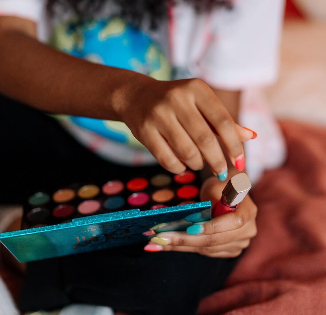 Woman with brightly colored nails holding a brightly colored makeup palette