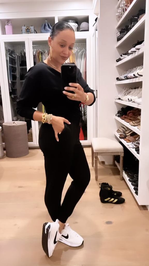 tia mowry wears a black outfit with white nike sneakers, shoe closet, gold jewelry, white and black sneakers