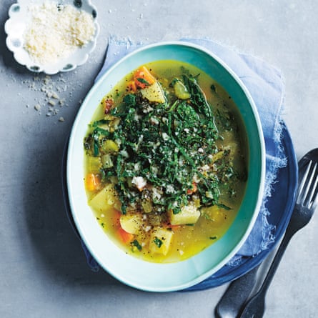 Above view of a oval bowl of chunky vegetable and be an soup topped with shredded cavolo nero and grated parmesan.