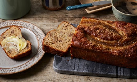 A loaf of banana bread, including a slice of banana bread on a plate, spread with butter.