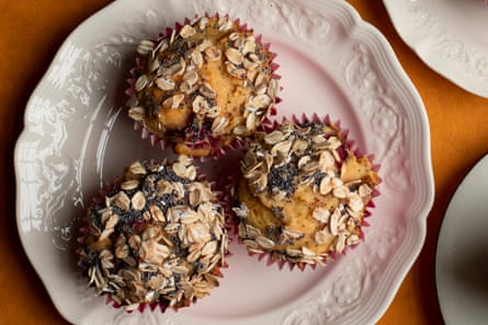 Three muffins topped with poppy seeds and oats on a white plate.