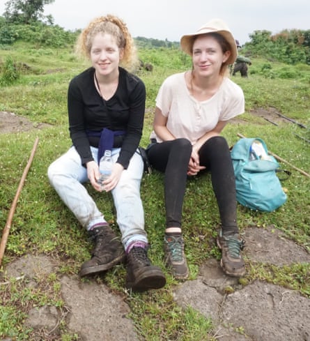 Two young women in hiking gear sitting on the ground in a national park. 