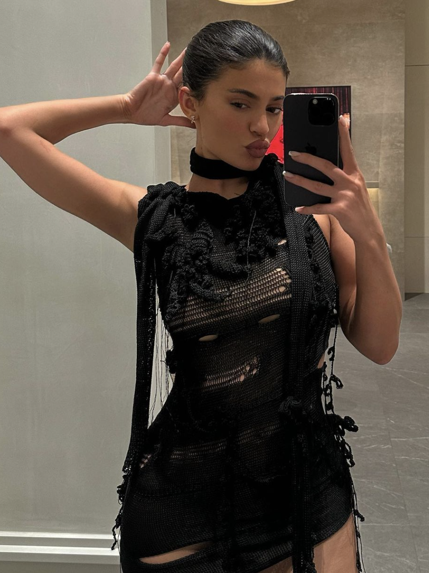 Kylie Jenner taking a mirror selfie in her distressed dress.