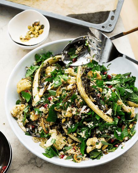 A large white plate with cauliflower, pomegranate and pistachio salad.