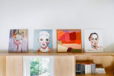 Paintings that sit in Kylie’s office, painted by her husband, Ben Quilty, and her son Joe Quilty. Joe’s self-portrait sits second from the left.