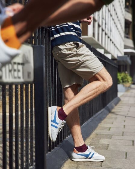 Man leaning against a iron fence, showing off the best ankle socks from London Sock Co. Blurry ankle in the top left.