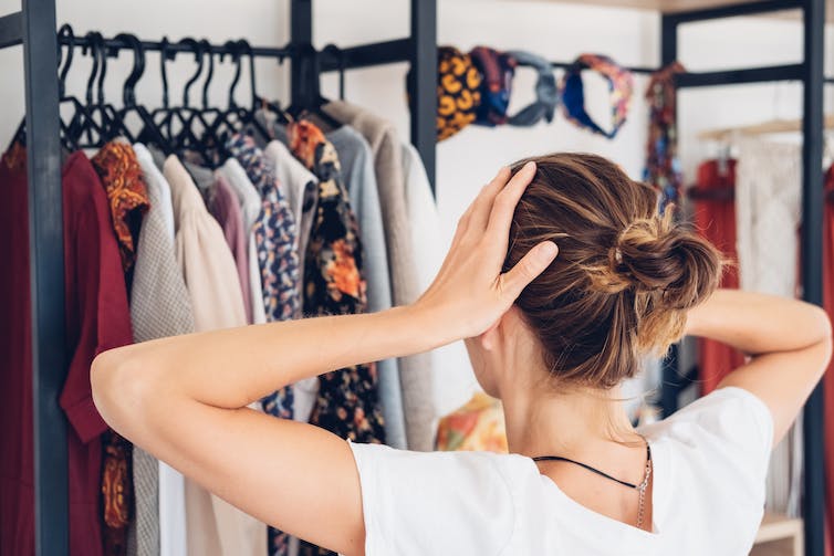 Woman near her wardrobe with her hands on her head.