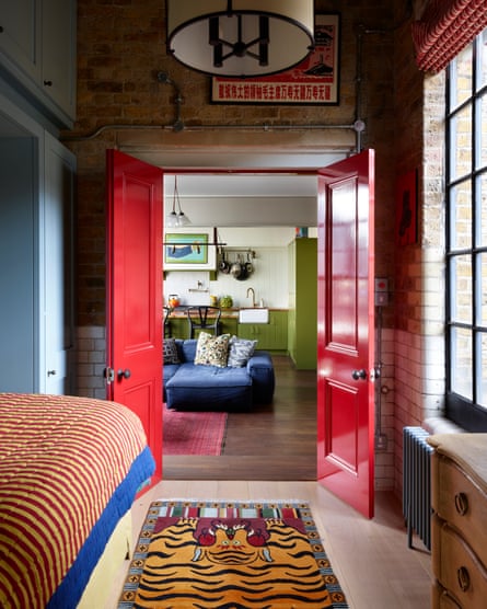 Double doors painted red frame the living room, with the green kitchen beyond