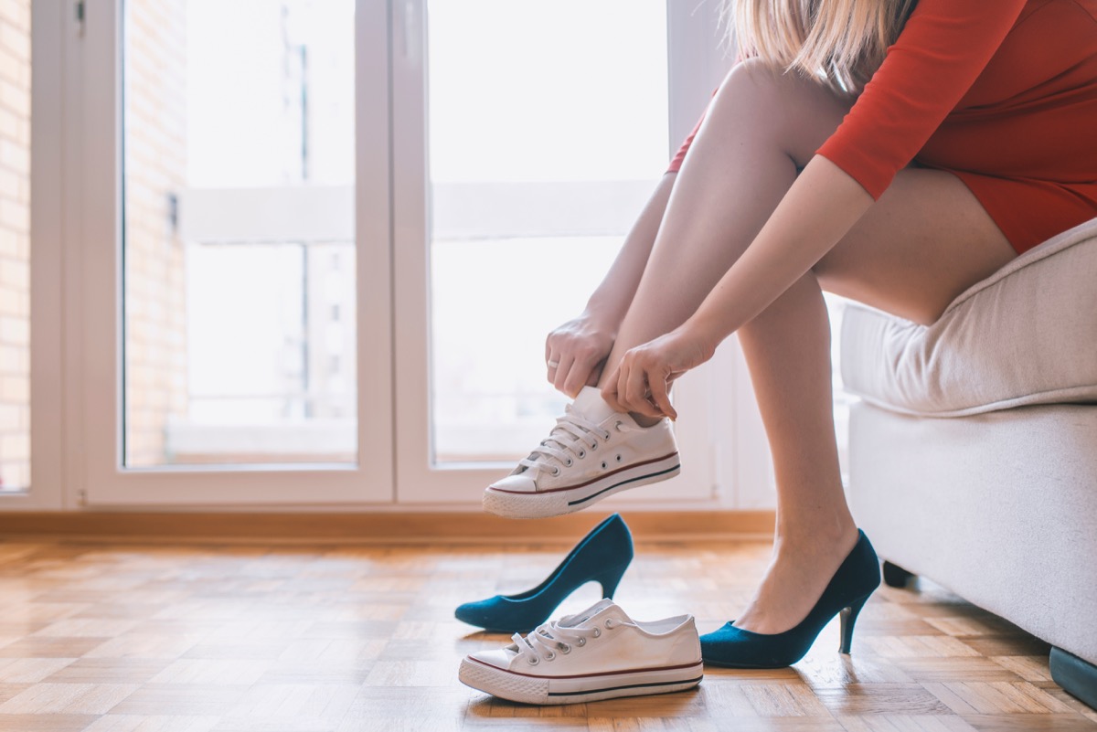 woman changing from heels into sneakers inside her home