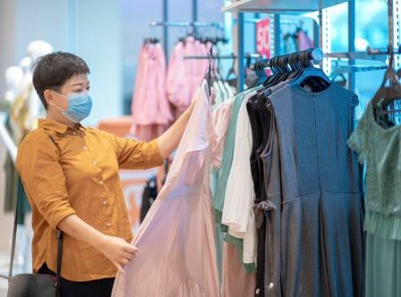 female hand holding dress and looking at clothing store choosing