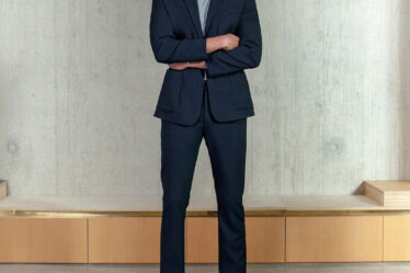 tall man wearing a navy suit and white sneakers