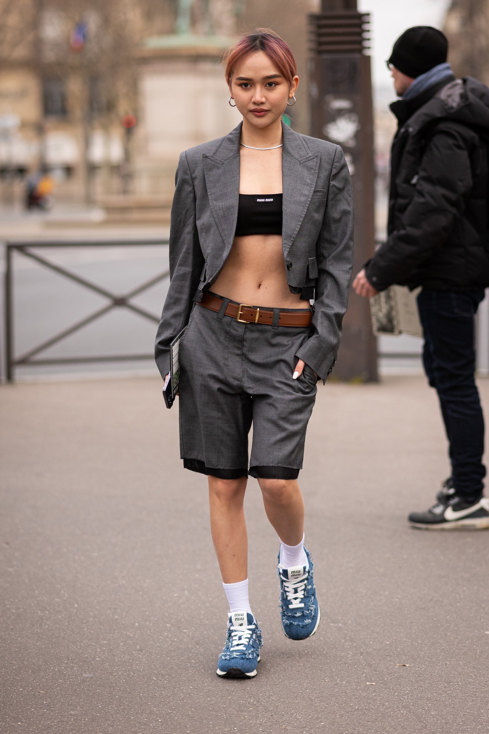 PARIS FRANCE  MARCH 07 Christinna Kuan wears a grey blazer with matching shorts Miu Miu black crop top and Miu Miu x New...