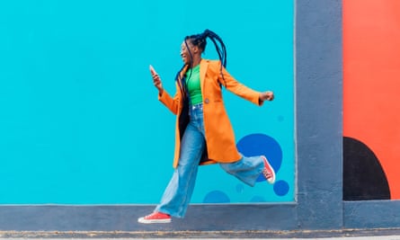 Woman in colourful clothes jumping against backdrop of blue wall