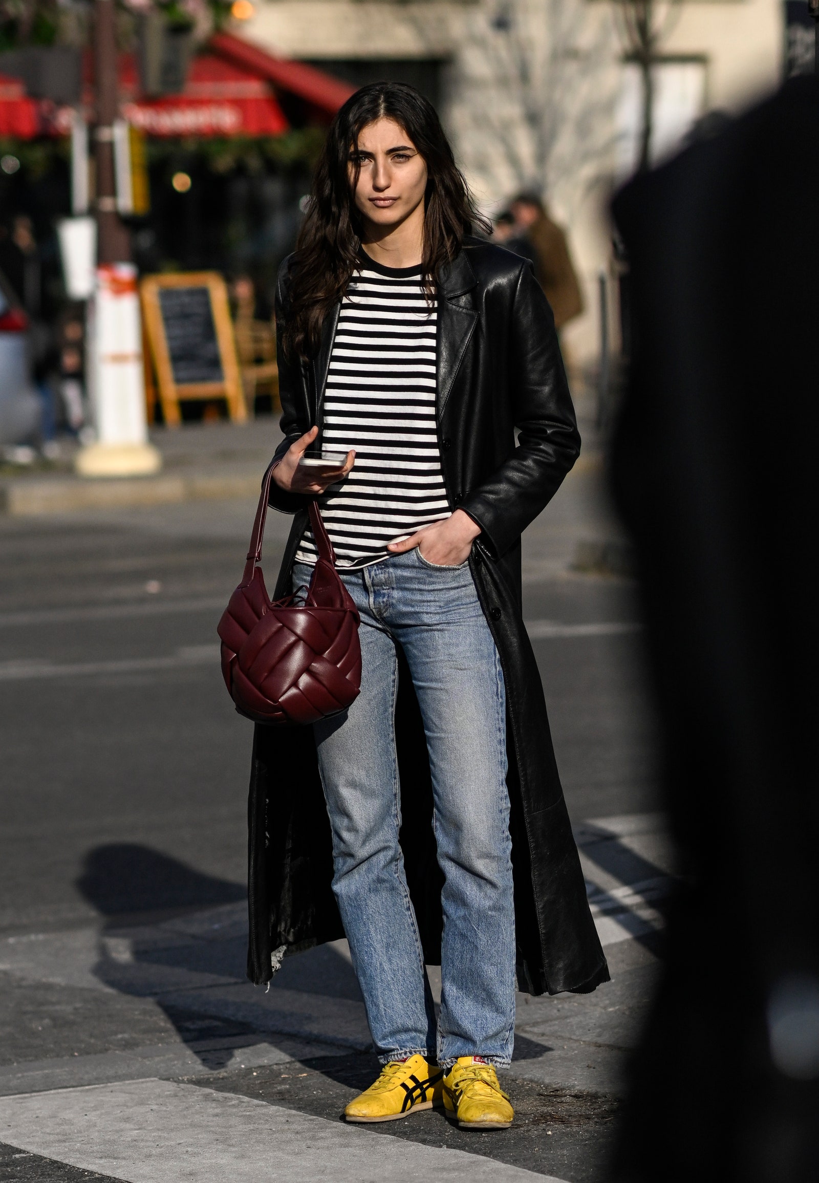 PARIS FRANCE  MARCH 01 A model is seen wearing a black leather coat black and white striped shirt blue jeans and yellow...