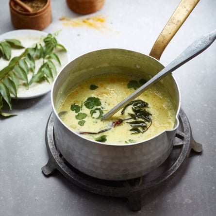 A metal saucepan containing khaddi, a South Asian yoghurt soup, garnished with curry leaves.