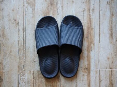 black slide sandals on wooden floor