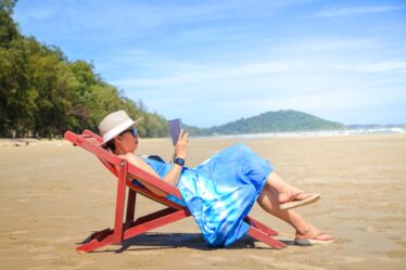 stylish woman wearing a blue long dress. Sit in the sunshine at the seaside looking at the beautiful natural scenery. Tourist sea beach Thailand, Asia, Summer holiday vacation travel trip