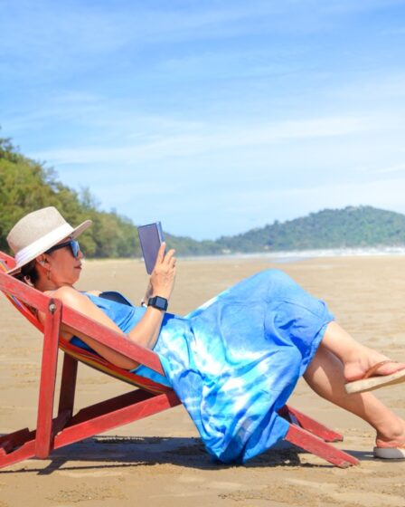 stylish woman wearing a blue long dress. Sit in the sunshine at the seaside looking at the beautiful natural scenery. Tourist sea beach Thailand, Asia, Summer holiday vacation travel trip