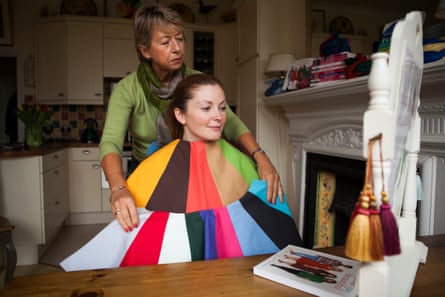 A woman is draped in different coloured fabrics to determine which shades complement her skin tone.