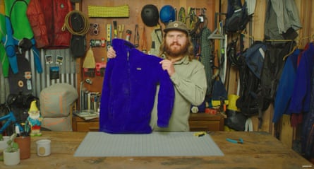 A screengrab of a Patagonia video on how to fix zipper sliders, with a bearded man holding up a blue outdoor jacket in a garment repair workshop.