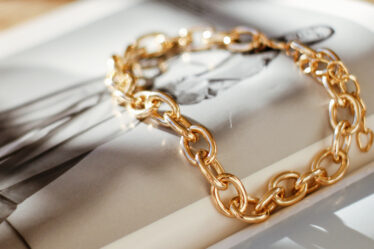 the world of jewelry nati melnychuk unsplash photo of gold chain on fashion magazine spread