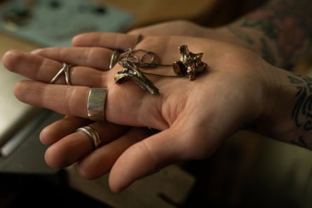Ace Tilton Ratcliff holds jewelry they made of their deceased pets’ bones.