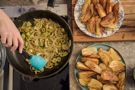 A hand stirring chopped sauteed onions and fennel, with fried fennel wedges on a plate on the side.
