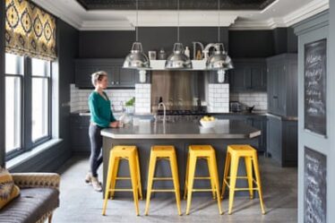 Creative space: Ann Marie in the kitchen, with its aluminium worktop, yellow Wayfair stools and BTC pendant lights.