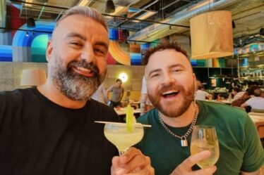 Two men holding alcoholic drinks on a celebratory night out.