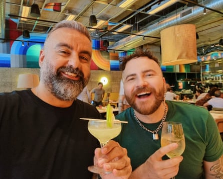 Two men holding alcoholic drinks on a celebratory night out.