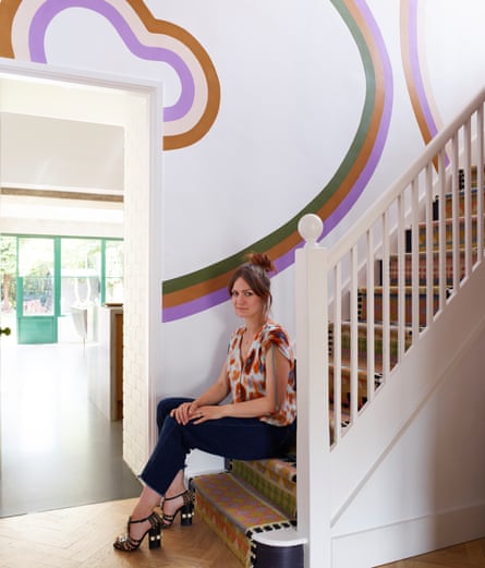 Hayley sitting at the bottom of the stairs, colourful shapes on the hall wall.