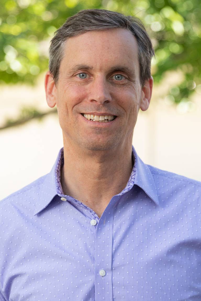 Headshot of CMO of Auberge Resorts, Mike Minchin, in a blue shirt.