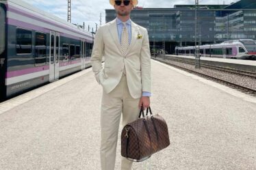 man in a white suit carrying a weekend bag
