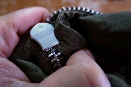 Fix a stuck zipperA close up of stuck zipper on a dark green jacket, holding by a hand