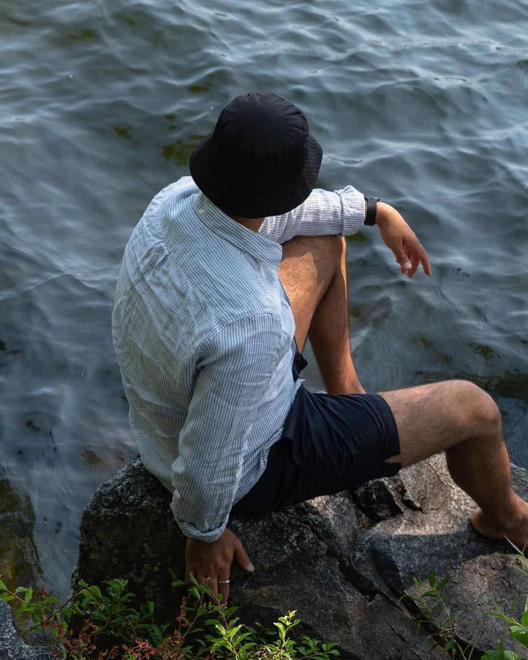 man sitting on the rocks by the water