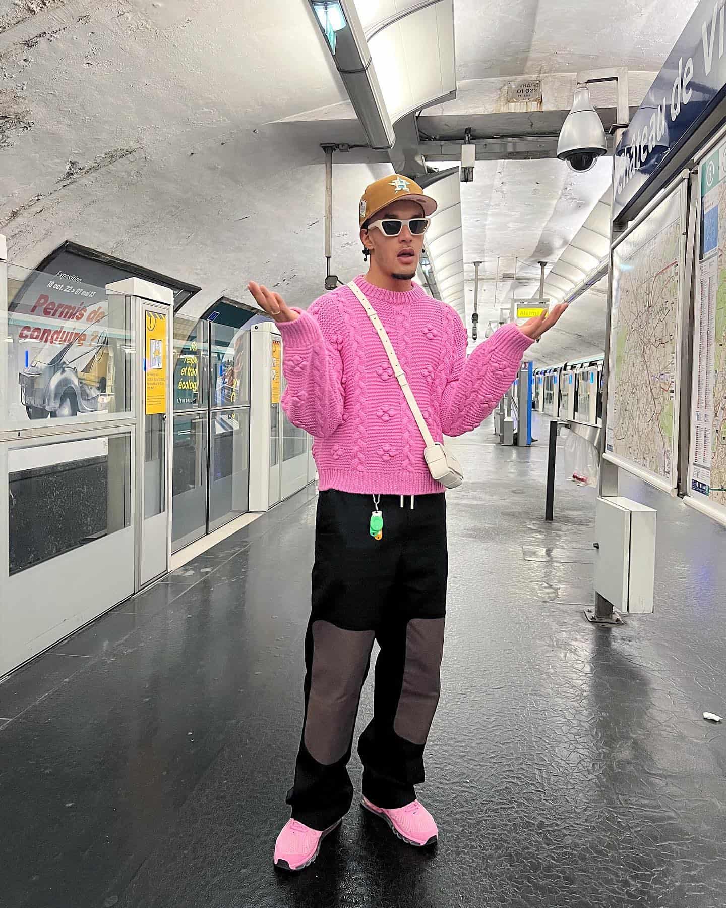 man in a subway station wearing a pink knit jumper