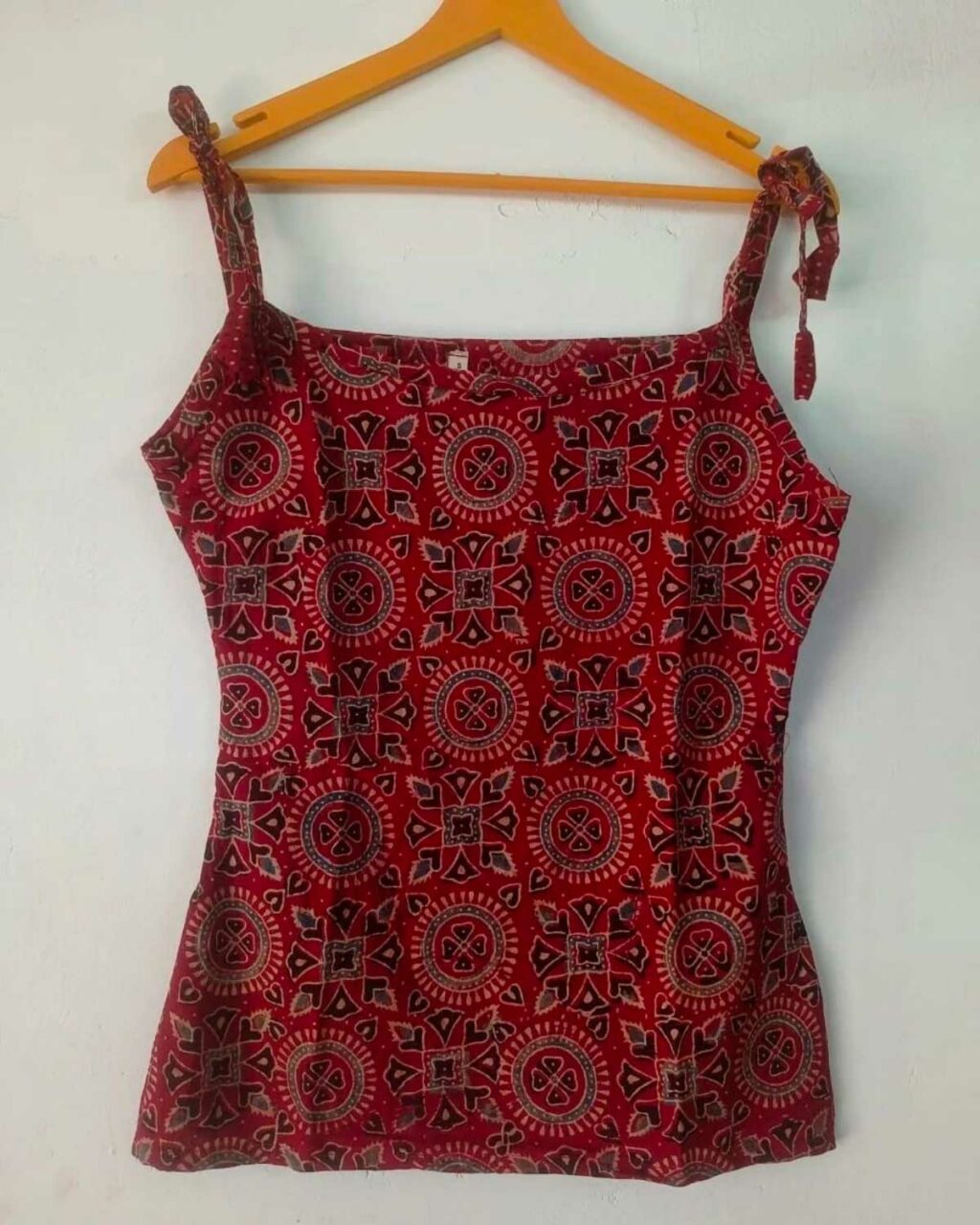 Red Camisoles hanging on a hanger, perfect for summer weather.