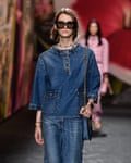 A model wearing a boxy denim top with jeans and sunglasses