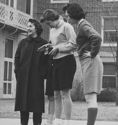Black and white photo of four young women, three of whom are wearing shorts.