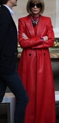 Anna Wintor, arms crossed and wearing sunglasses and a long trench coat, looking serious