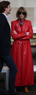 Anna Wintor, arms crossed and wearing sunglasses and a long trench coat, looking serious