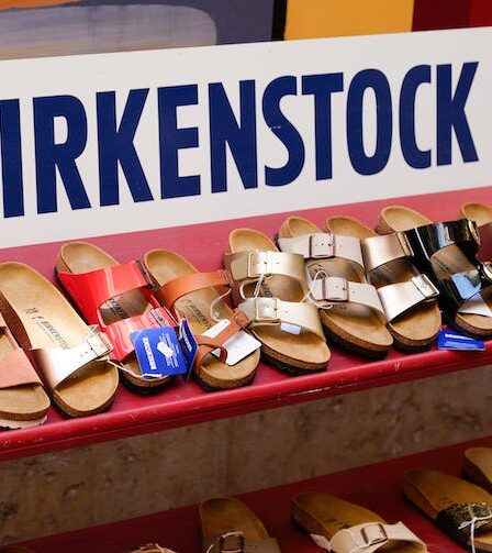 A shop shelf holding different Birkenstock styles and colours below a Birkenstock sign.