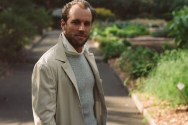 A stylish man in a beige jacket and grey knit jumper