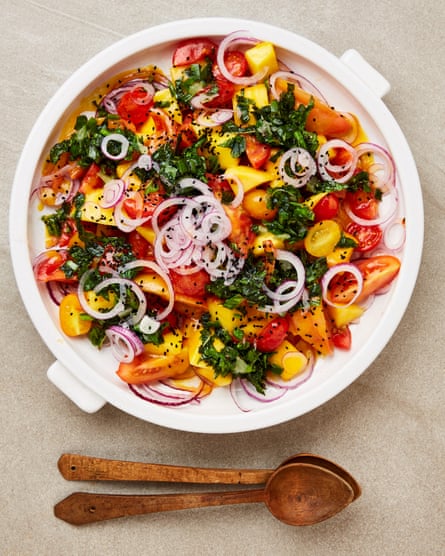 Yotam Ottolenghi’s tomatoes with mango miso dressing, in a bowl with two wooden spoons
