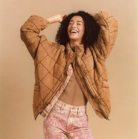 Model in rust quilted coat, with pink jeans and jacket